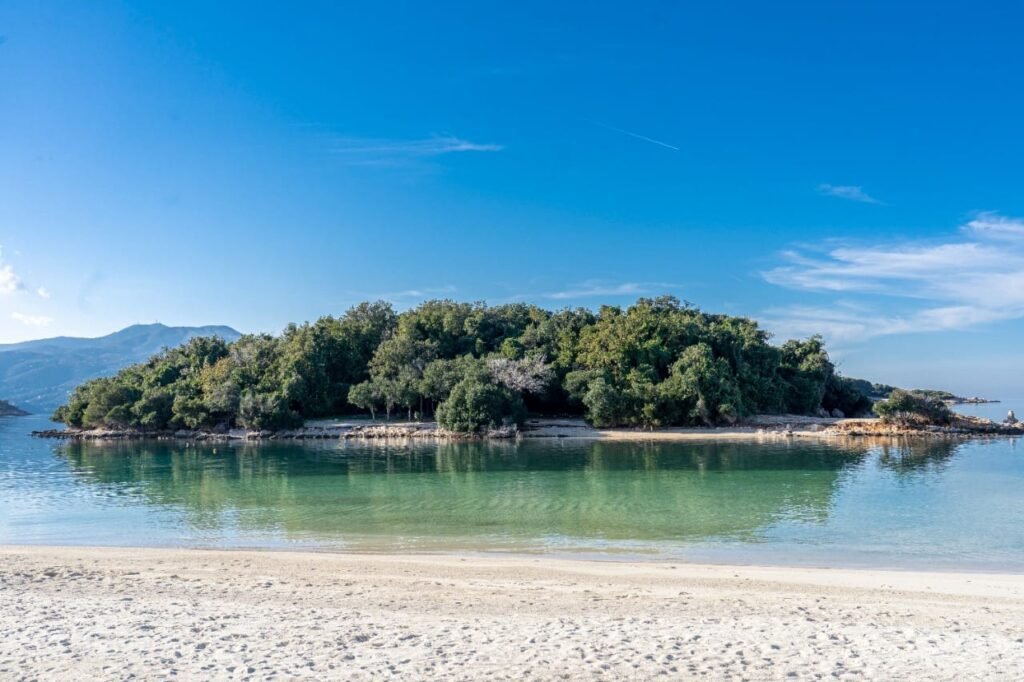 Ksamil Beach, showing white sand, crystal-clear turquoise waters and the island with big greenery