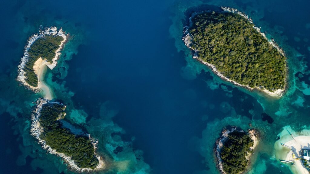 Drone perspective of the four Ksamil islands, revealing their lush greenery set against azure blue waters