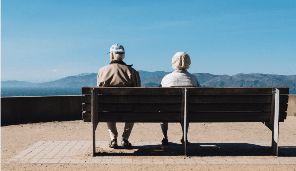 two elderly people sitting on a bench, enjoying the stunning mountain views