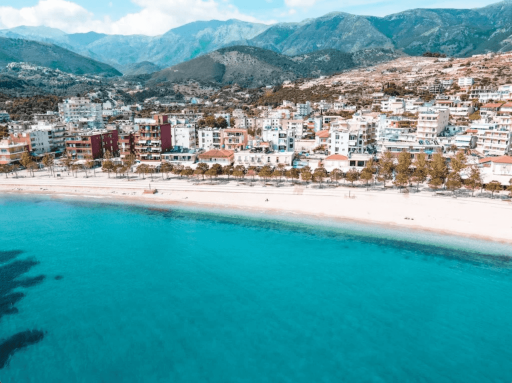 drone view of Himare Albania showing the urban architectire , sandy beach coast and crystal clear waters and mountains