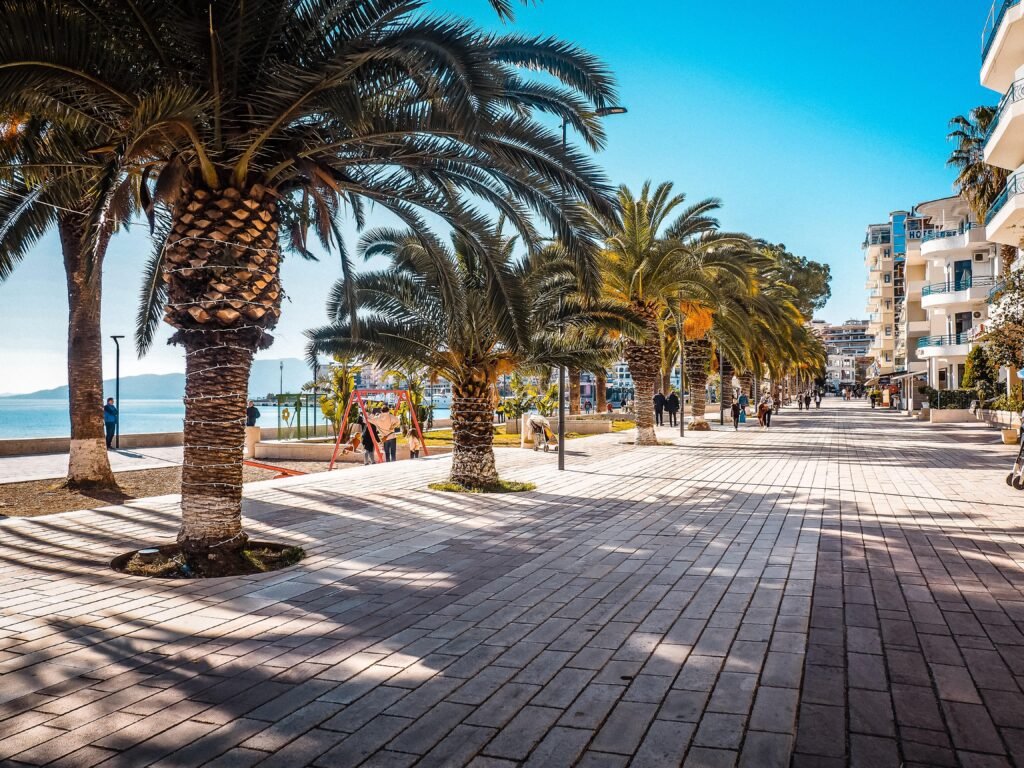 promenade of saranda, albania in the day time with big palms, hotels and the sea in front