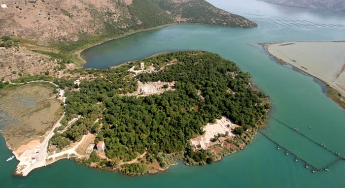 drone view of the ancient city of butrint in saranda albania and the blue lake and forest with the ancient sculptures