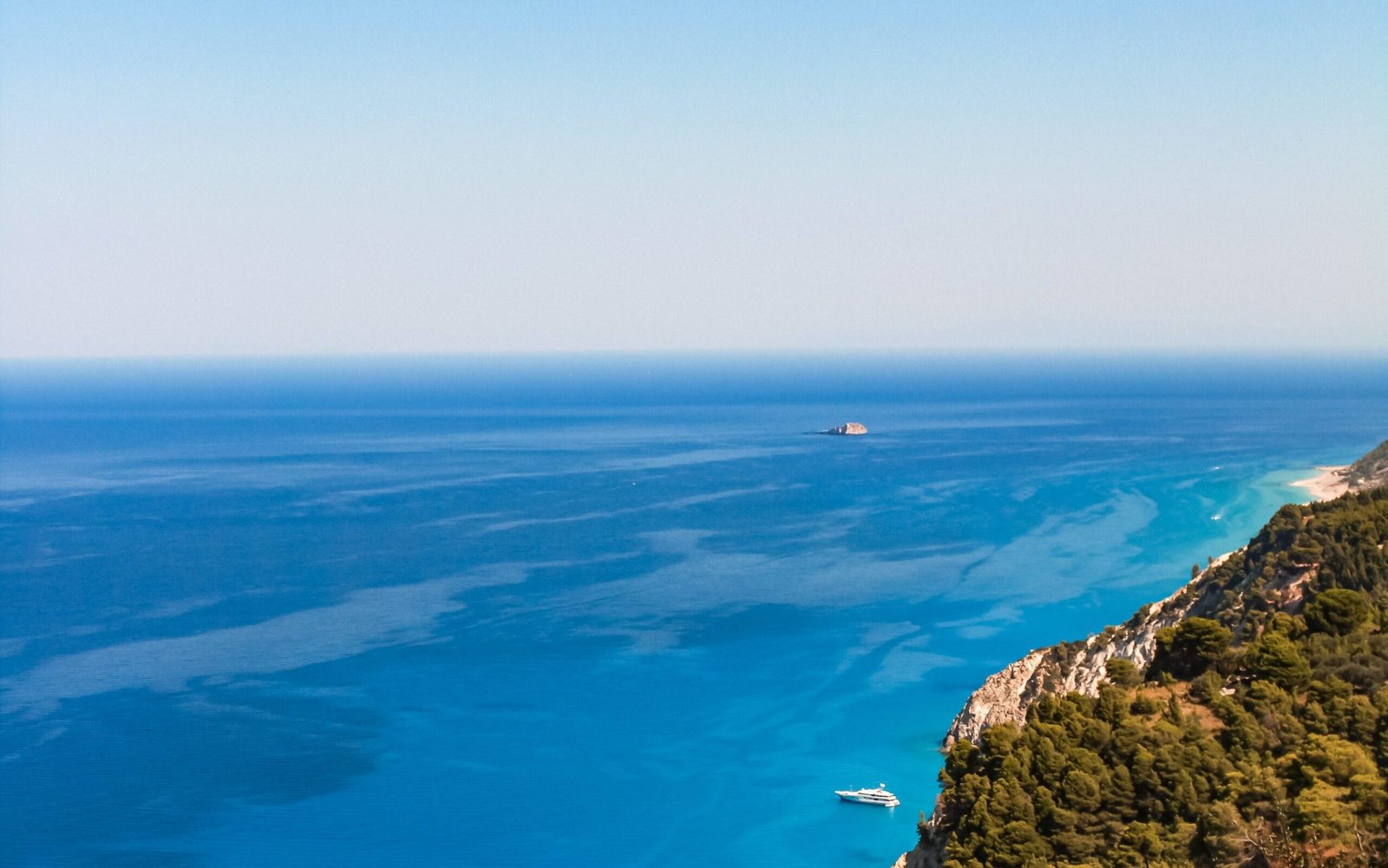 aerial drone view of the green coast in albania in the ionian see showcasing the crystal clear waters , green nature and yachts sailing