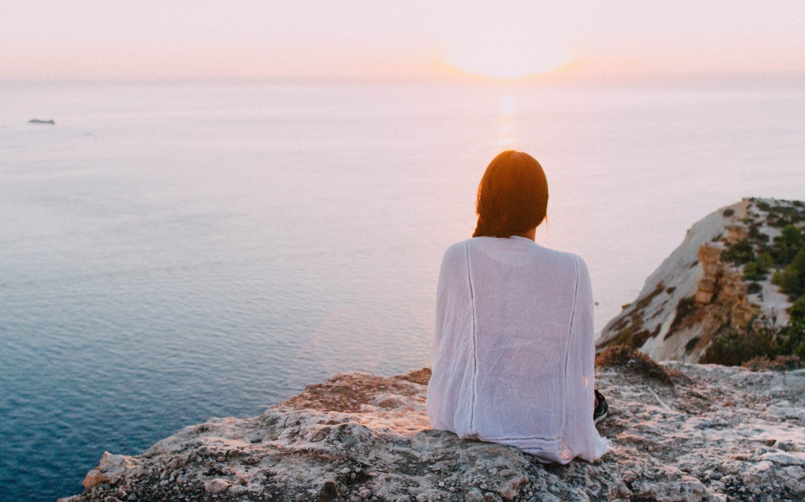 a girl sitting on top of a hill on a sunset in saranda albania