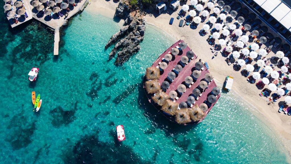 ksamil beach aerial picture showing the sunbeds, boats and people relaxing in the shore