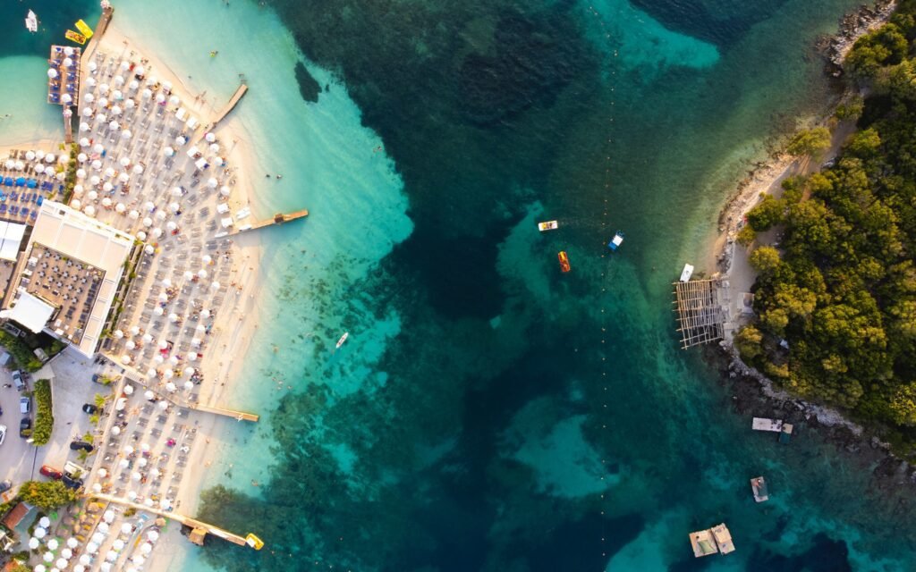 ksamil islands aerial view of the 3 islands and the city center beach shore with sunbeds and restaurant with people and boats