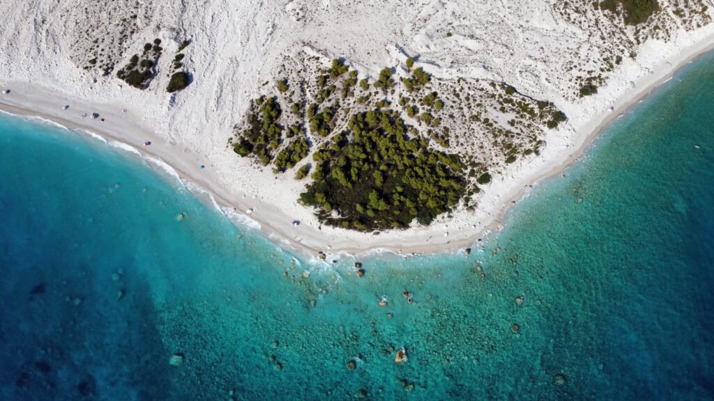 himare, pristine white sandy beach framed by vibrant blue waters and lush greenery.